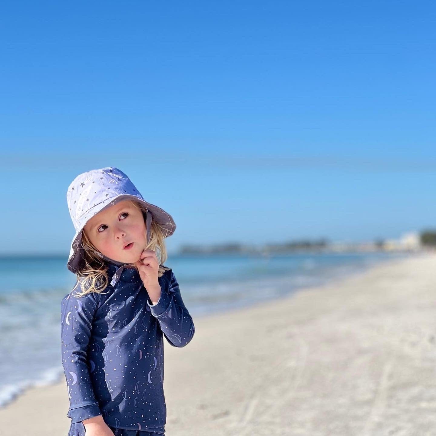 toddler boy with bucket hat on Anna Maria Island blue water white sand beach