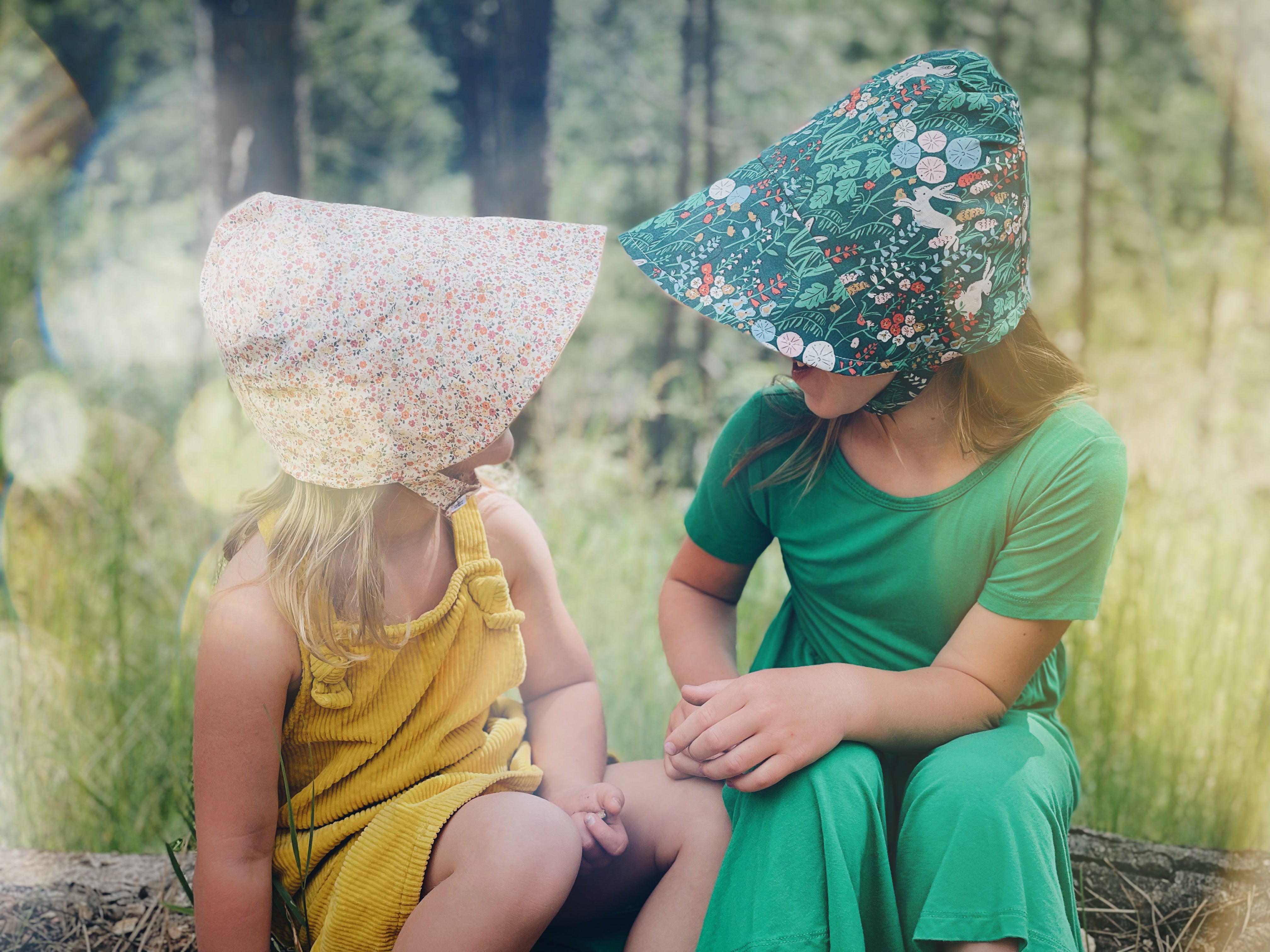 two little girls wearing baby bonnets holding hearing aids in protect port wine stain birthmark