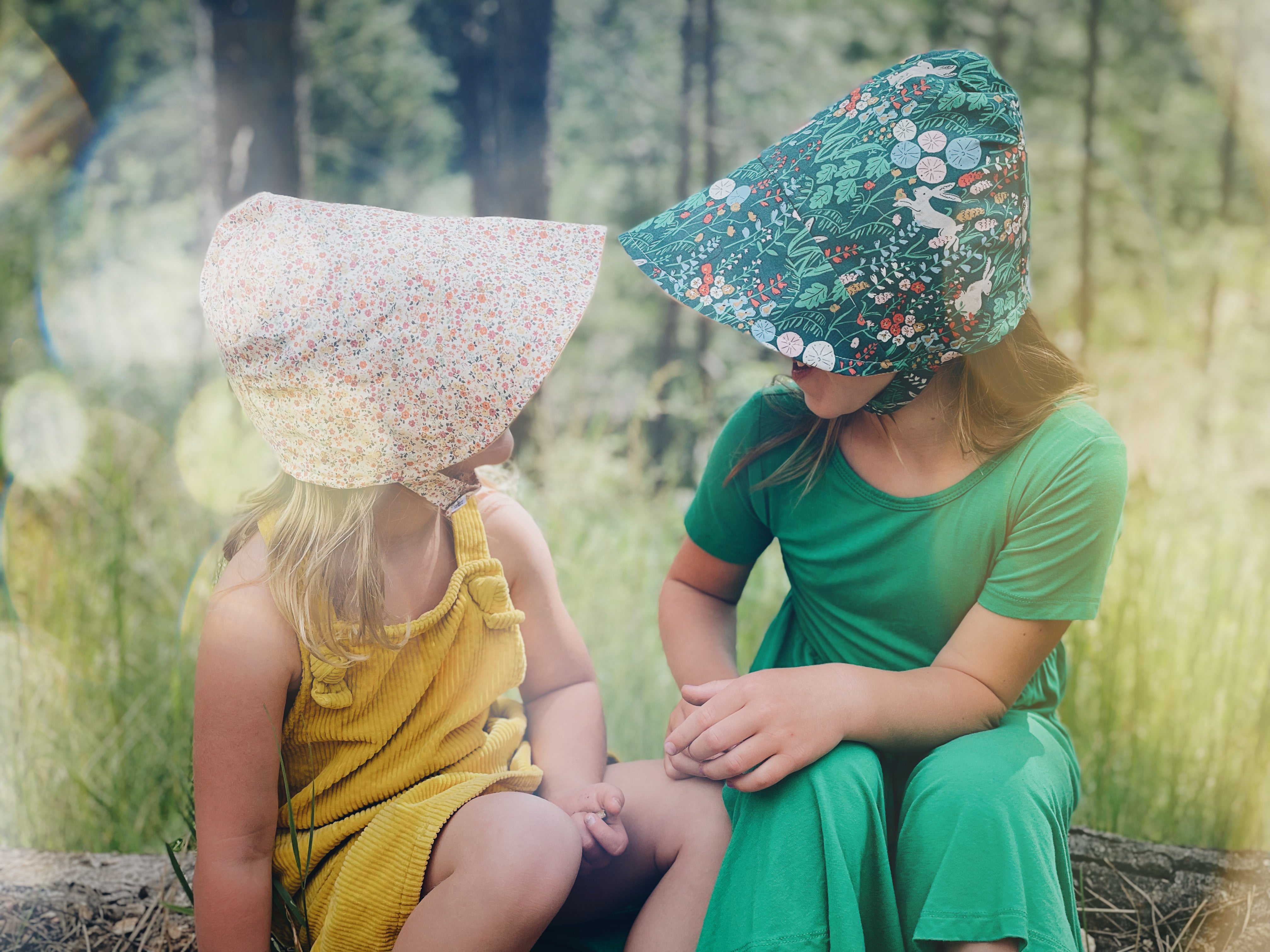 two little girls wearing baby bonnets holding hearing aids in protect port wine stain birthmark